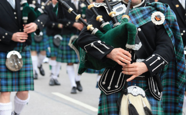 » Country Heritage Tours Parade of bagpipe players marching while wearing kilts