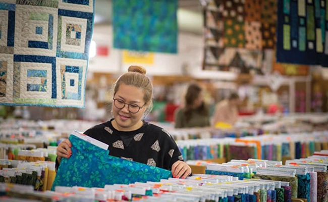 » Country Heritage Tours Woman inspecting yards of fabric in a quilting store