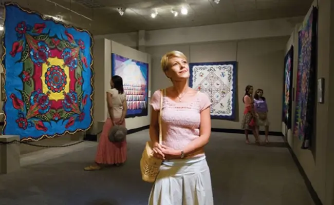 » Country Heritage Tours Woman strolling through a quilting museum looking at exhibits