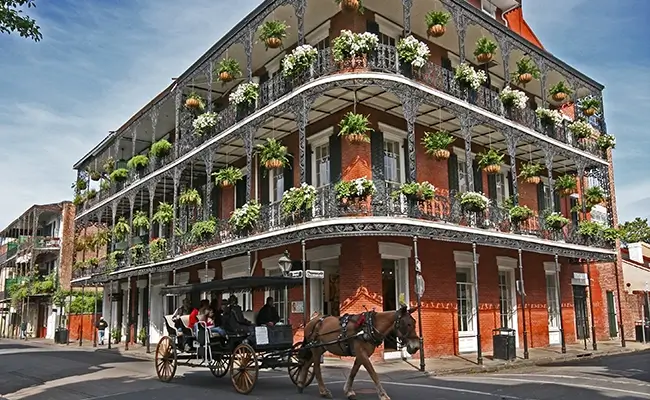 » Country Heritage Tours New Orleans building with wraparound porches and hanging plants