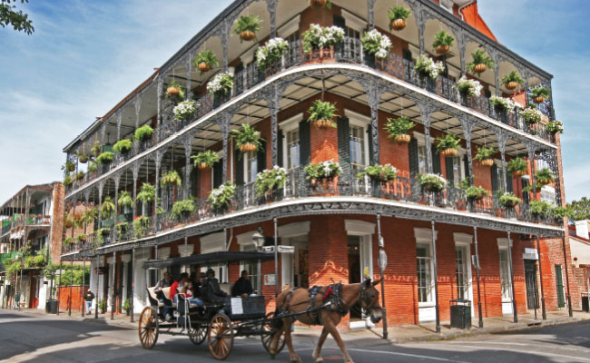 » Country Heritage Tours New Orleans building with wraparound porches and hanging plants