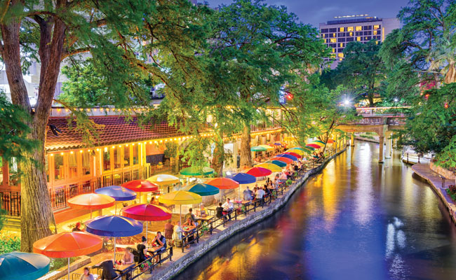 » Country Heritage Tours Colorful umbrellas with dining tables lining a river in a city Riverwalk