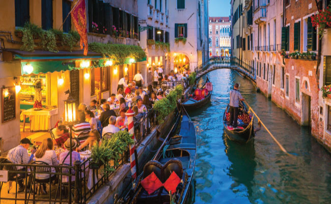 » Country Heritage Tours Waterway in Venice with gondola boat and people dining waterside