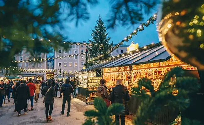 » Country Heritage Tours People strolling through a European Christmas market with holiday lights