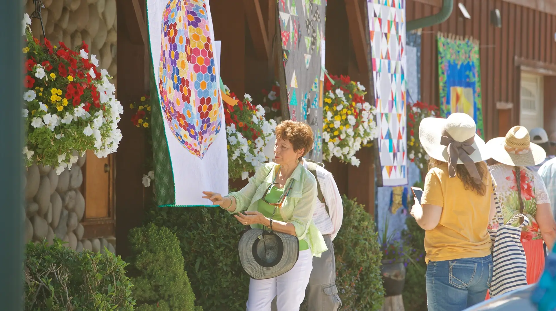» Country Heritage Tours » Country Heritage Tours Woman inspecting a quilt hung outside of a rustic museum