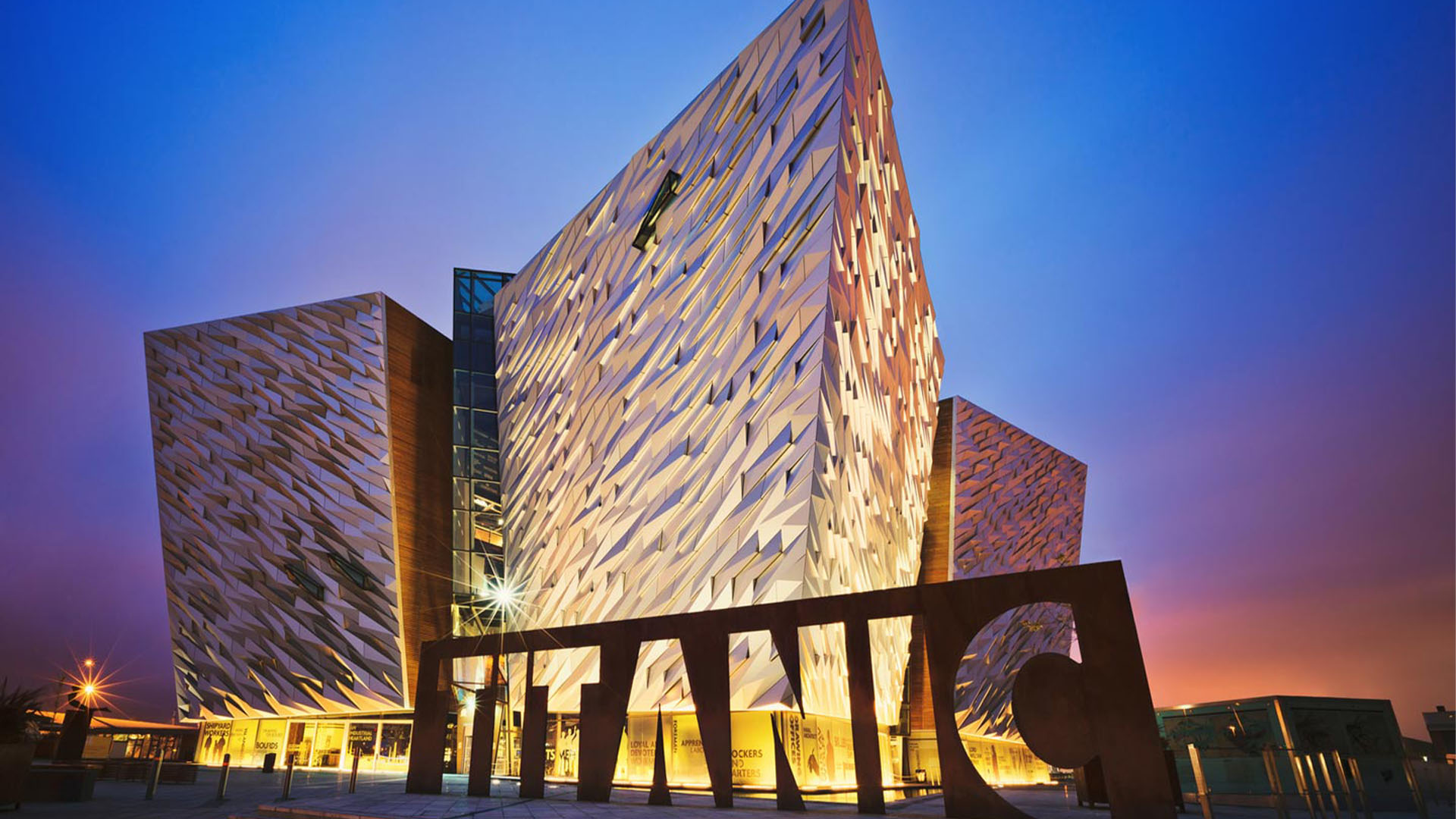 » Country Heritage Tours Angular modern museum with a jagged patterned facade at sunset, large LAC sculpture in the foreground