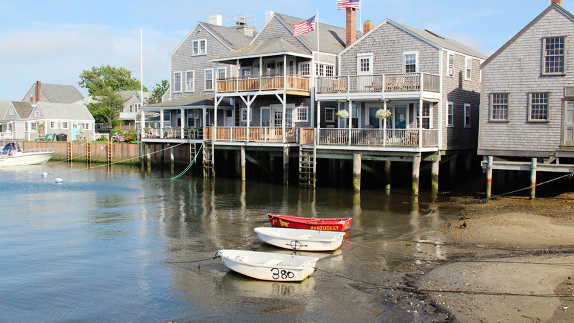 » Country Heritage Tours Row of gray clapboard houses on stilts over calm harbor, with small boats in the foreground.